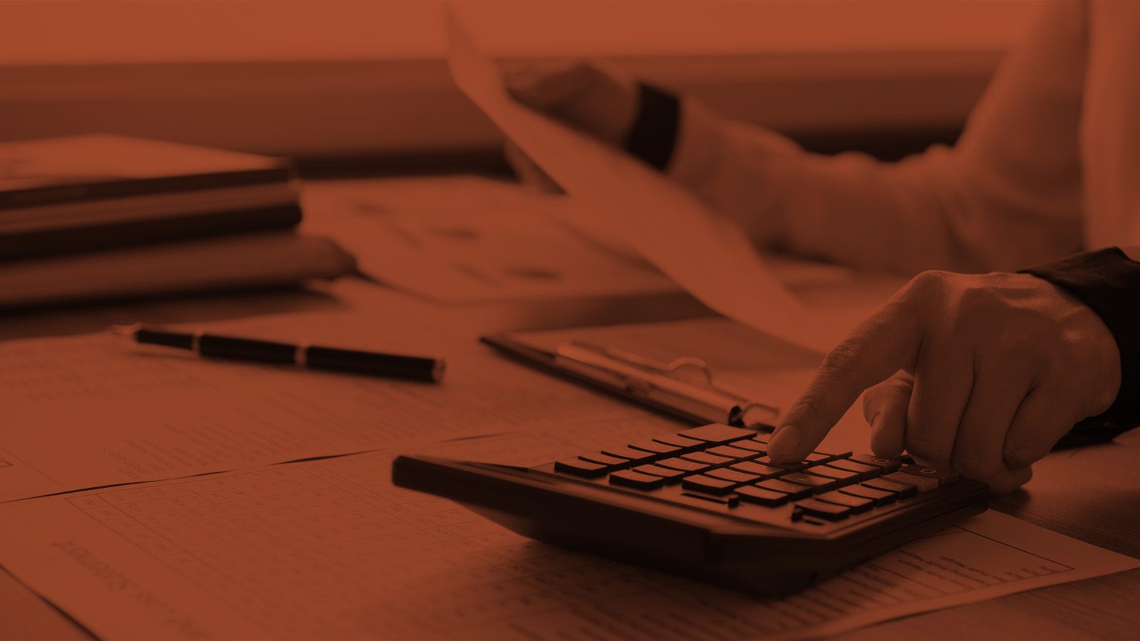 Is Search Marketing More Effective Than Traditional Advertising? Feature Image: Person at Desk Looking at Spreadsheets and Working a Calculator